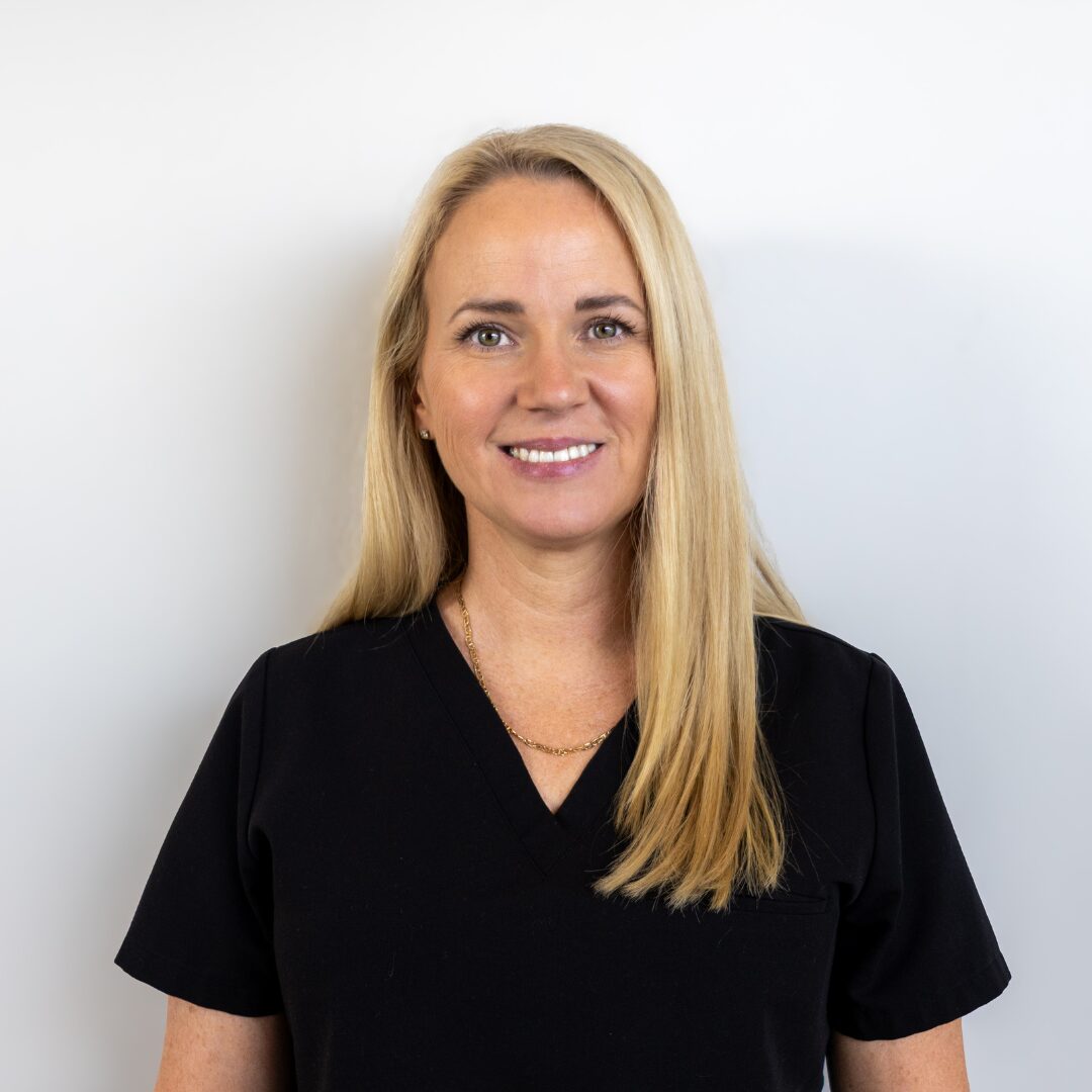 Elaina Williamson, APRN, MSN, FNP-C, a nurse practitioner at Silique Companies, smiling in black scrubs with long blonde hair.