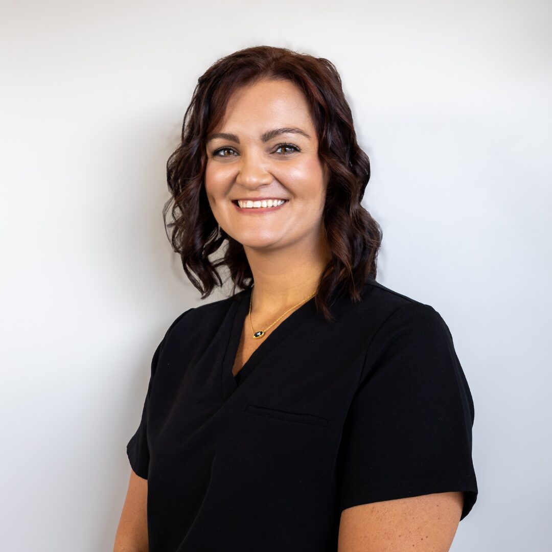 Kristyn Neely, LPN, a licensed practical nurse at Silique Companies, smiling in black scrubs and a gold necklace.