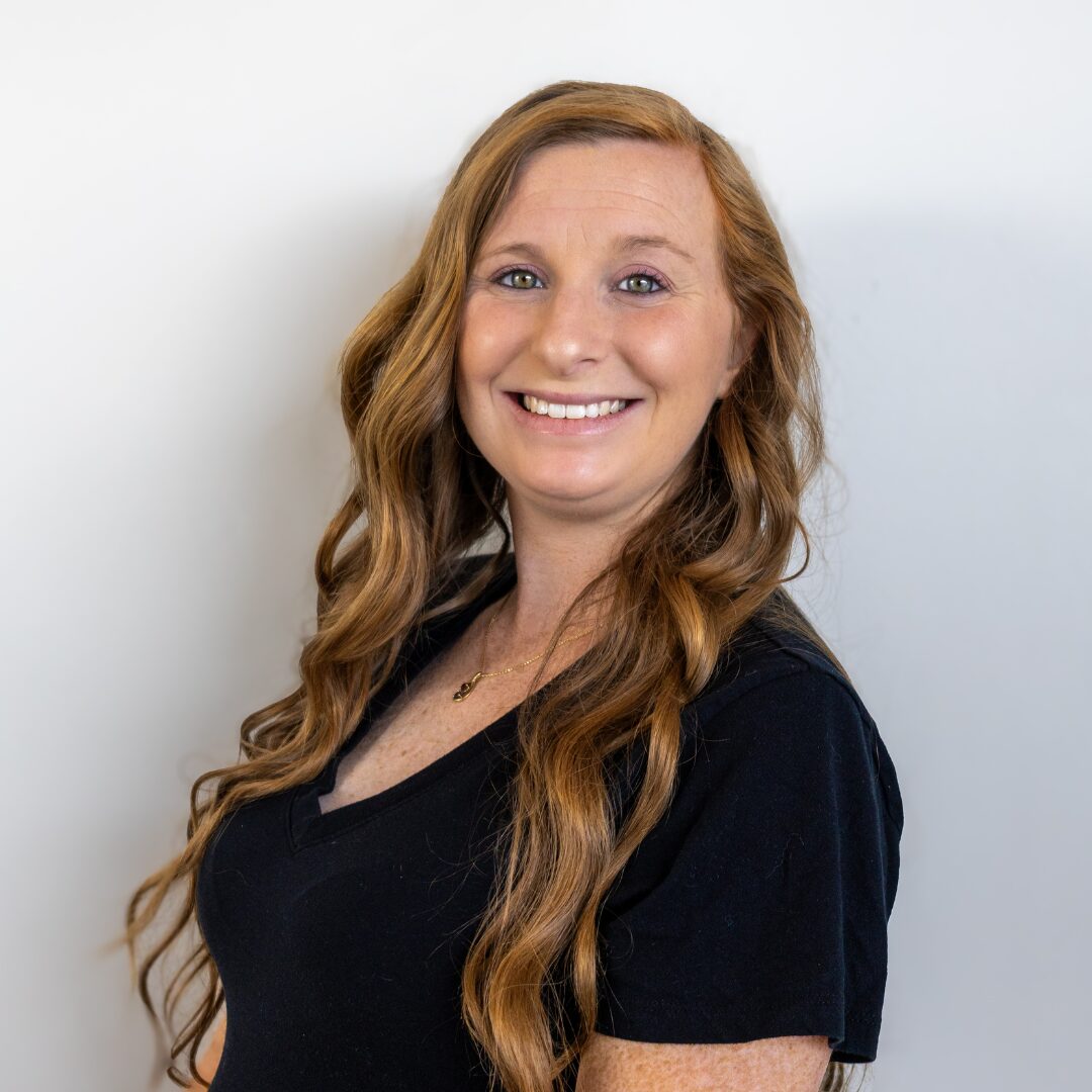 Kayla Fridley, APRN, MSN, FNP-C, a nurse practitioner at Silique Companies, smiling in a black top with long, wavy auburn hair.